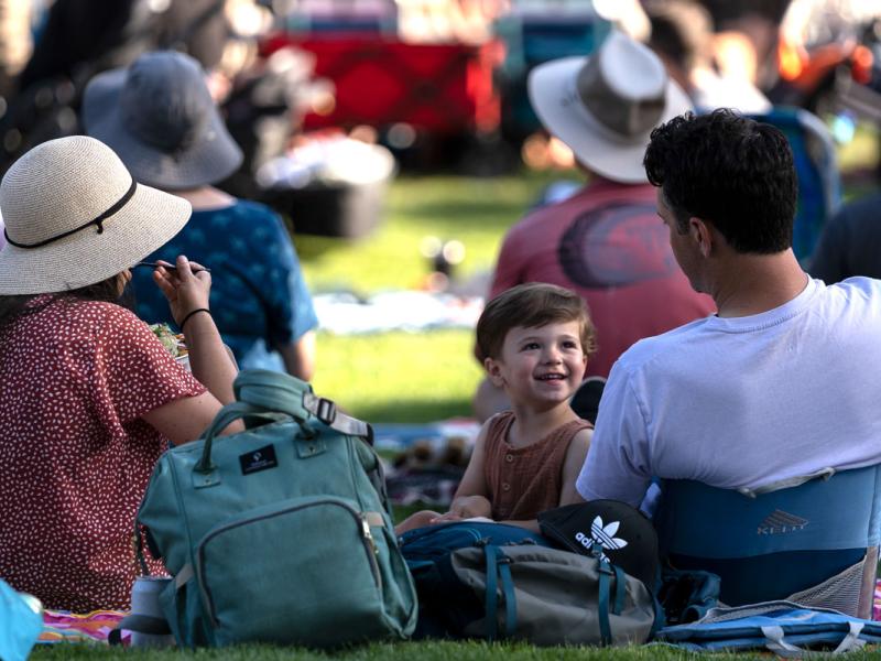 A family sits on the concert lawn. 