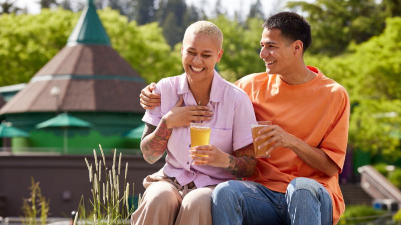 A couple drinks beer together on the concert lawn. 