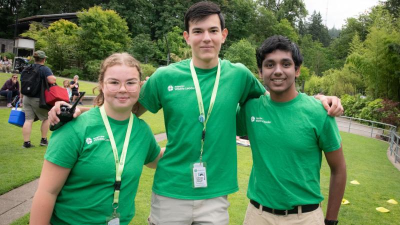 Three young people in green shirts standing outside