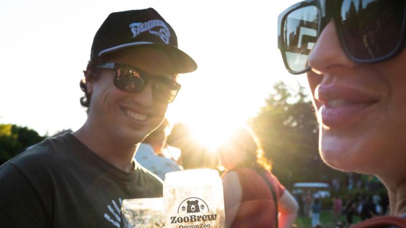 guests clinking beer glasses together with sun setting in background