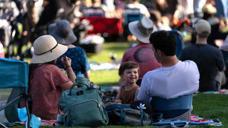 family on amphitheater lawn in summer enjoying food