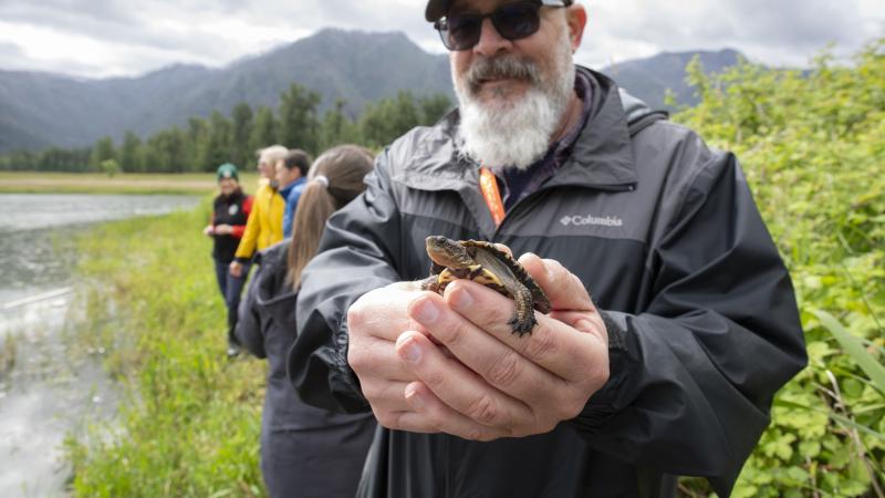 a bearded white man holding a turtle