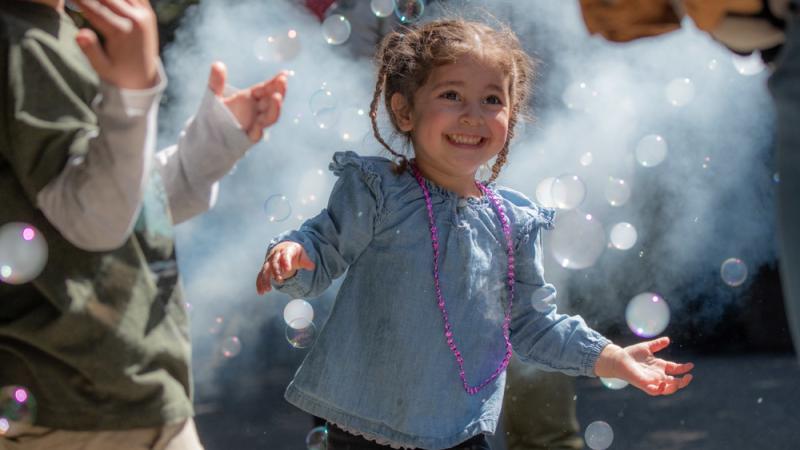 A girl smiles as she is surrounded by bubbles. 