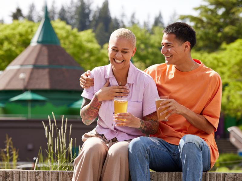 A couple drinks beer together on the concert lawn. 