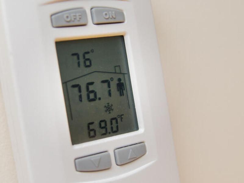 A wall thermostat shows the temperature set to 69 degrees Farenheit.