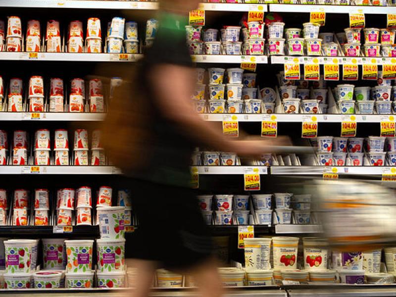 A person pushes a cart down the aisle of a grocery store.