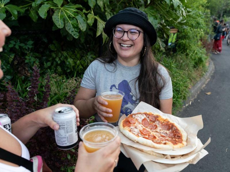 young adult visitors laughing with pizza and beer