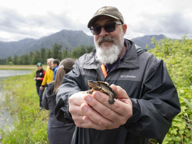 a bearded white man holding a turtle