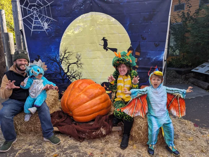 family dressed as dinosaurs sitting around a pumpkin