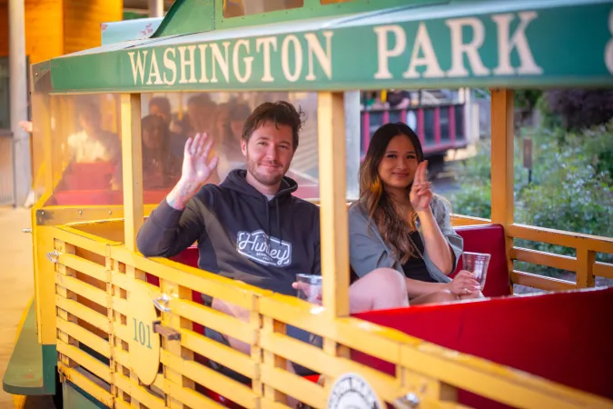 Guests ride the zoo train, waving as they ride.